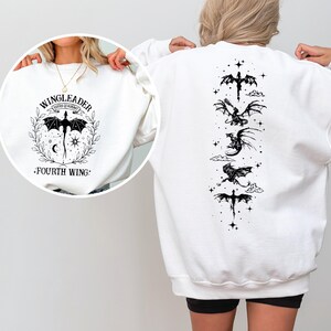 A person wearing a white sweatshirt with a graphic design featuring a dragon and stars on the back.