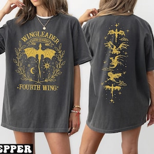 A woman wearing a grey t-shirt with a graphic design featuring a dragon and the text "WINGLEADER" and "FOURTH WING".