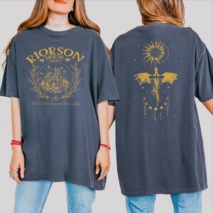 A woman wearing a gray t-shirt with a graphic design on the front and a dragon design on the back.