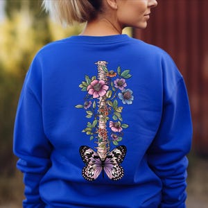a woman wearing a blue sweatshirt with a butterfly on it