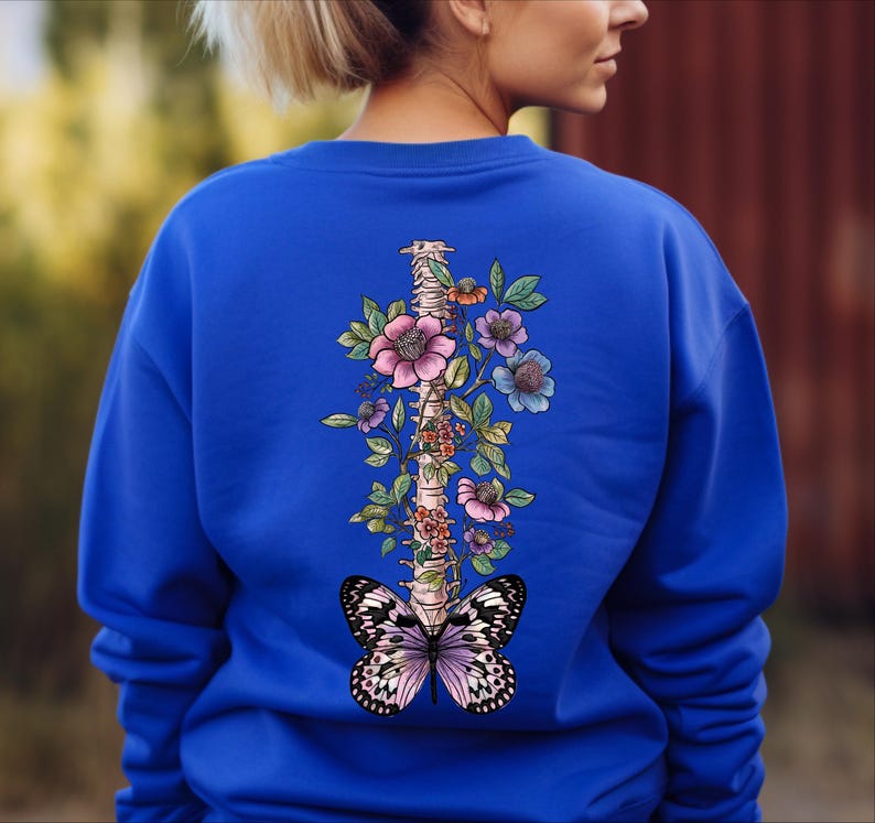 a woman wearing a blue sweatshirt with a butterfly on it