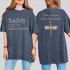 A woman wearing a blue t-shirt with text and a graphic on the back.