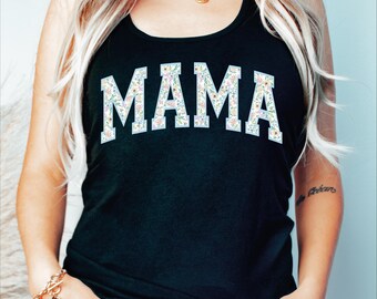 May include: A black tank top with the word "MAMA" printed in white letters outlined in blue. The letters are filled with a floral pattern in shades of pink, yellow, and green.