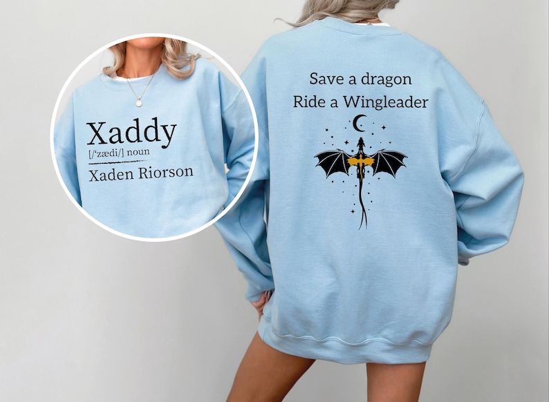 A woman wearing a light blue sweatshirt with a dragon design and text printed on the back.