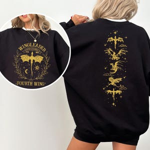 A woman wearing a black sweatshirt with a gold dragon design and text on the back.