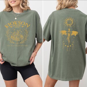 A woman wearing a green t-shirt with a graphic design on the front and back.