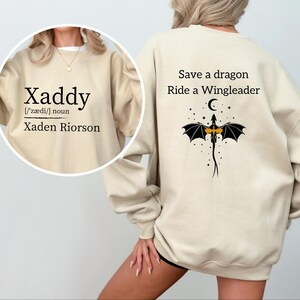 A person wearing a beige sweatshirt with text and a graphic design on the back.
