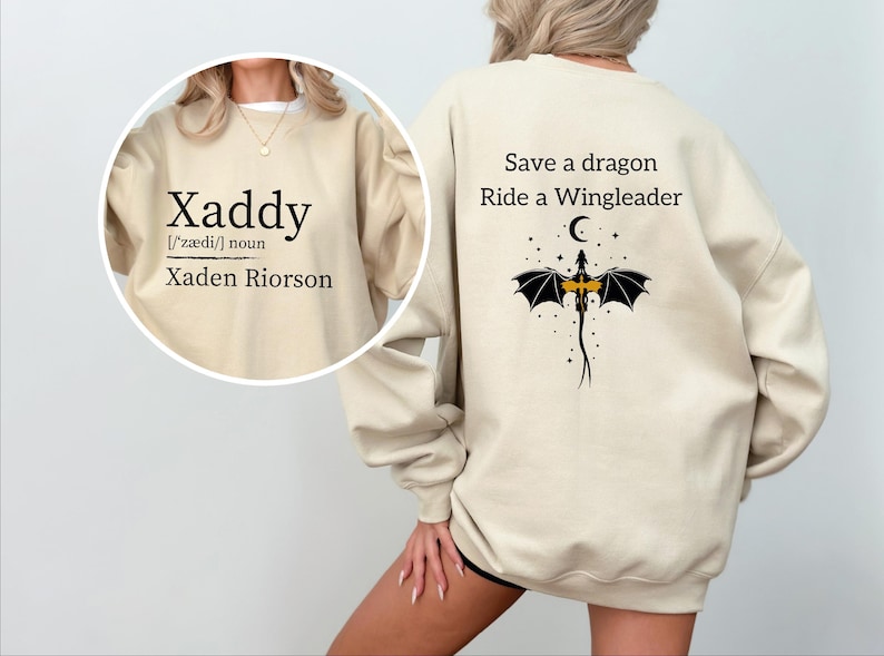 A person wearing a beige sweatshirt with text and a graphic design on the back.