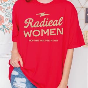 a woman wearing a red shirt that says radical women