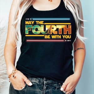 May include: A black tank top with the text "May the Fourth Be With You" in yellow and white letters. The text is stylized to look like the Star Wars logo.