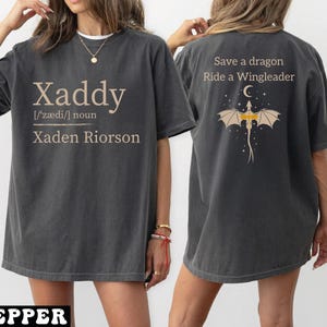 A woman wearing a gray t-shirt with text and a dragon graphic on the back.