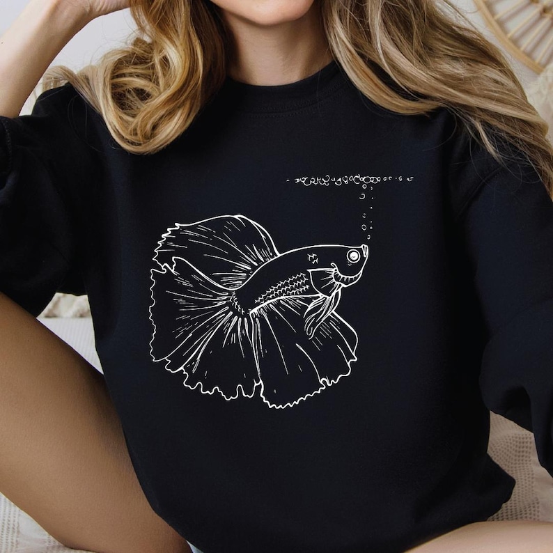 a woman wearing a black shirt with a picture of a fish on it