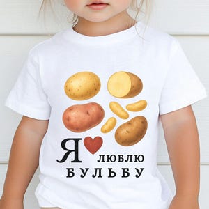 May include: White t-shirt featuring a watercolor illustration of various potatoes. The shirt has the text "I love potatoes" in Russian. The design includes whole and sliced potatoes in shades of brown and yellow.