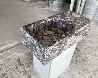 May include: A white and purple marble sink with a rectangular shape. The sink is mounted on a white pedestal.