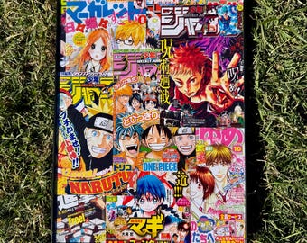 May include: A framed collage of colorful Japanese manga magazine covers. The artwork features various anime characters with bold colors and dynamic compositions. The frame is black, and the background is green grass.