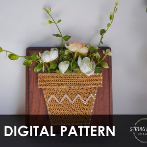 May include: A digital pattern for string art featuring a potted plant with white and peach flowers. The pattern is on a brown wooden background. The text "DIGITAL PATTERN" is at the bottom of the image. The text "STRING WORKS ART & DESIGN" is in a circle at the bottom right of the image.