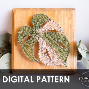 Puede incluir: Un patrón digital para arte de hilo con una hoja de monstera verde y blanca sobre un fondo de madera. El patrón se titula "DIGITAL PATTERN" e incluye el texto "String Works Art & Design".
