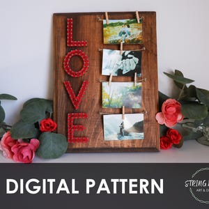 以下が含まれることがあります： 赤い糸アートで「LOVE」の文字が書かれた木製の写真ディスプレイ。 ミニ洗濯バサミで留められた4枚の小さな写真が飾られています。 ディスプレイは緑とピンクのバラに囲まれています。 下部には「DIGITAL PATTERN」の文字があります。