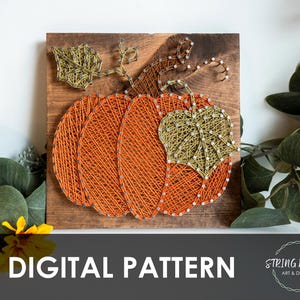 Può includere: Zucca string art su una tavola di legno. La zucca è arancione con uno stelo e una foglia verdi. Le parole "DIGITAL PATTERN" sono in basso nell'immagine. Il design è di String Works Art & Design.