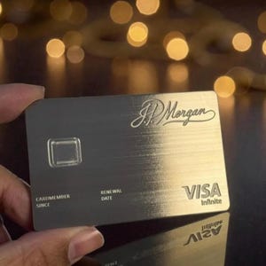 Op de afbeelding: Een zilveren creditcard met het JP Morgan-logo en het Visa Infinite-logo. De kaart heeft een geborstelde metalen afwerking en bevat de tekst "CARDMEMBER SINCE" en "RENEWAL DATE".