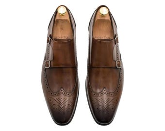 Zapatos de vestir tipo monje, estilo brogue, con hebilla y puntera de ala, hechos a mano en cuero marrón con pátina.