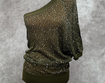 May include: An olive green one-shoulder top featuring a loose, draped fit and a knit fabric densely covered in small, shimmering silver sequins. The garment includes a wide, solid-colored ribbed hem and a matching ribbed neckline trim.
