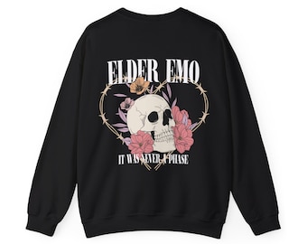 May include: Black sweatshirt featuring a skull graphic with pink and yellow flowers inside a heart-shaped barbed wire design. The text "ELDER EMO" and "IT WAS NEVER A PHASE" are printed above and below the skull.