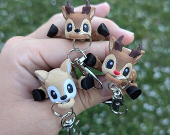 May include: Three brown and tan deer keychains with black hooves and white eyes. Each keychain has a silver metal ring and clip.