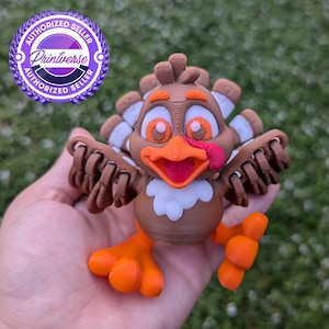 May include: A 3D printed turkey figurine with brown, orange, and white paint. The turkey has a friendly expression with a red tongue sticking out.