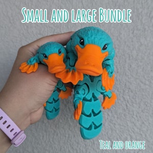 May include: A teal and orange platypus toy bundle. The bundle includes a small and a large platypus toy. The toys are made of plastic and have a textured surface.