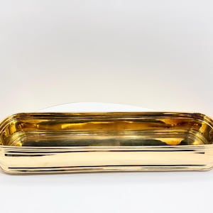 May include: A rectangular, gold-colored metal planter. The planter has a shiny, reflective surface and a series of horizontal ridges along its sides. The interior is also gold, creating a cohesive and elegant look. The planter is empty.