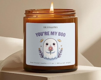 May include: A brown glass candle with a white label that says "HIGHS&LOWS YOU'RE MY BOO". The label features a cartoon ghost holding a pink flower. The candle is hand-poured and weighs 7 ounces or 200 grams.