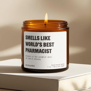 May include: A brown glass candle jar with a white label that reads "Smells Like World's Best Pharmacist". The label also includes the text "Breathe in the perfect dose of calm & clarity" and "HIGHS&JOWS Hand Poured Candle 7 oz | 200 g net weight".