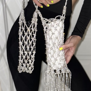 Può includere: Una borsa a catena di strass argentata con un dettaglio a frangia. La borsa è realizzata in materiale a rete e ha una tracolla lunga.