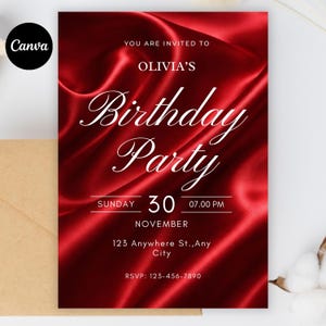 Op de afbeelding: Een rode verjaardagsfeestuitnodiging met witte scripttekst. De uitnodiging bevat de tekst "Olivia's Birthday Party", datum, tijd en RSVP-informatie. De achtergrond heeft een zijdeachtige textuur.