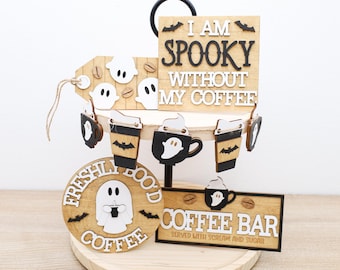 May include: A tiered Halloween-themed coffee bar display. The wooden display features signs with phrases like "I am spooky without my coffee" and "Coffee Bar." Decorative elements include ghost and bat cutouts, and coffee cup designs.