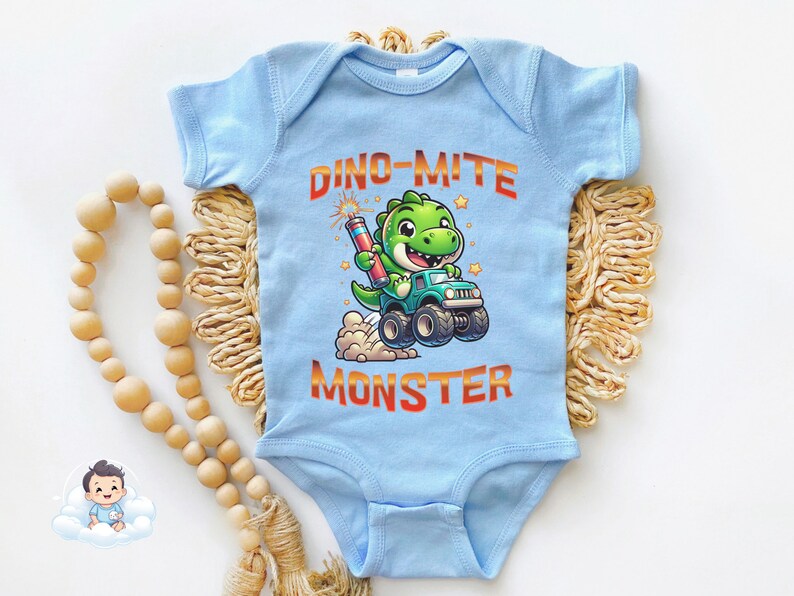 May include: A light blue baby onesie with a green dinosaur wearing a blue monster truck and holding a red firework. The text "Dino-mite Monster" is printed in orange on the onesie.