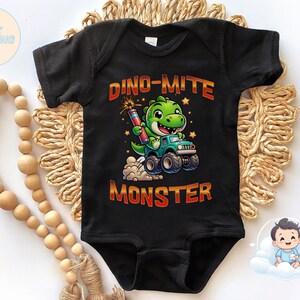 May include: Black short-sleeved bodysuit with a green dinosaur driving a monster truck. The text "Dino-mite Monster" is printed on the bodysuit.