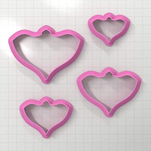 Può includere: Set di quattro tagliabiscotti in plastica rosa a forma di cuore con la parte superiore a punta.