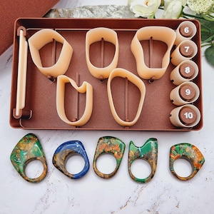 May include: A collection of resin rings in various colors and designs, alongside ring-making molds and sizing tools. The rings feature swirls of green, blue, and orange, with a glossy finish. The sizing tools are marked with numbers 6 through 10.