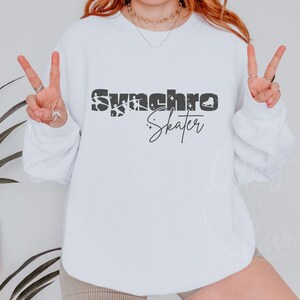 May include: White crewneck sweatshirt with the text "Synchro Skater" in black and gray lettering. The text is stylized with a distressed look and includes a small ice skate graphic.
