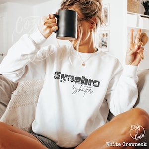 May include: White crewneck sweatshirt with the text "Synchro Skater" in black with a distressed effect.