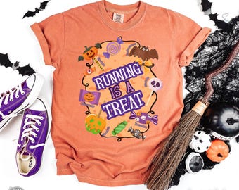 May include: Orange t-shirt with the phrase "Running is a Treat" in purple and white, surrounded by Halloween-themed graphics. Includes a bat, pumpkin, and candy. Purple Converse sneakers are visible on the left.