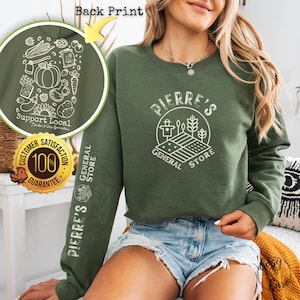 May include: Green sweatshirt with a white graphic of a farm scene and the text "PIERRE'S GENERAL STORE". The sweatshirt has a white graphic on the sleeve that says "PIERRE'S GENERAL STORE" and the text "Support Local" with a small graphic of farm produce.