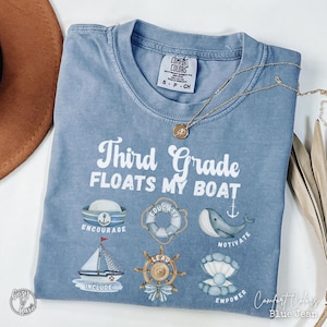 May include: Blue Comfort Colors t-shirt with the text "Third Grade Floats My Boat" and nautical-themed illustrations. The shirt includes the words "Encourage," "Educate," "Include," "Lead," "Motivate," and "Empower."