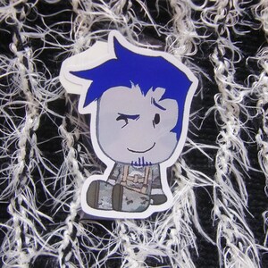 Puede incluir: Una pegatina con un personaje de dibujos animados con pelo azul y una expresi&oacute;n gui&ntilde;ando un ojo. El personaje lleva un atuendo gris con un arn&eacute;s. La pegatina est&aacute; sobre un fondo texturizado en blanco y negro.