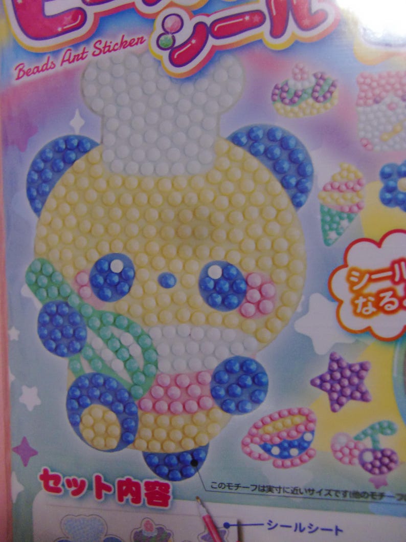 Pu&ograve; includere: Un set di adesivi colorati con un orso chef dei cartoni animati fatto di perline gialle, blu, rosa e bianche. Il set include vari disegni artistici con perline come coni gelato, stelle e ciliegie. Il testo "Beads Ant Sticken" &egrave; visibile.