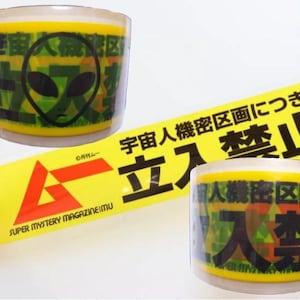 May include: Yellow tape rolls featuring alien head graphics and Japanese text. The tape reads "SUPER MYSTERY MAGAZINE IMU" and "No Entry" in Japanese. The alien head is black with large eyes.