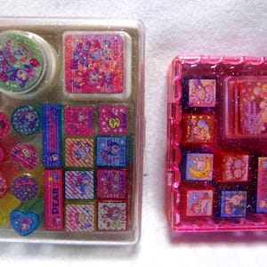 Puede incluir: Dos juegos de sellos decorativos en estuches de plástico transparente y rosa. Los sellos presentan personajes de dibujos animados y patrones coloridos en rosa, azul y verde. Un juego incluye una almohadilla de tinta redonda y varias formas.