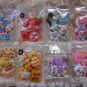 Peut inclure: Une collection de huit sacs en plastique transparents remplis de breloques miniatures colorées de style kawaii. Chaque sac contient une variété de formes, notamment des fleurs, des cœurs, des personnages et des bonbons. Certains sacs ont le texte "Sweet".